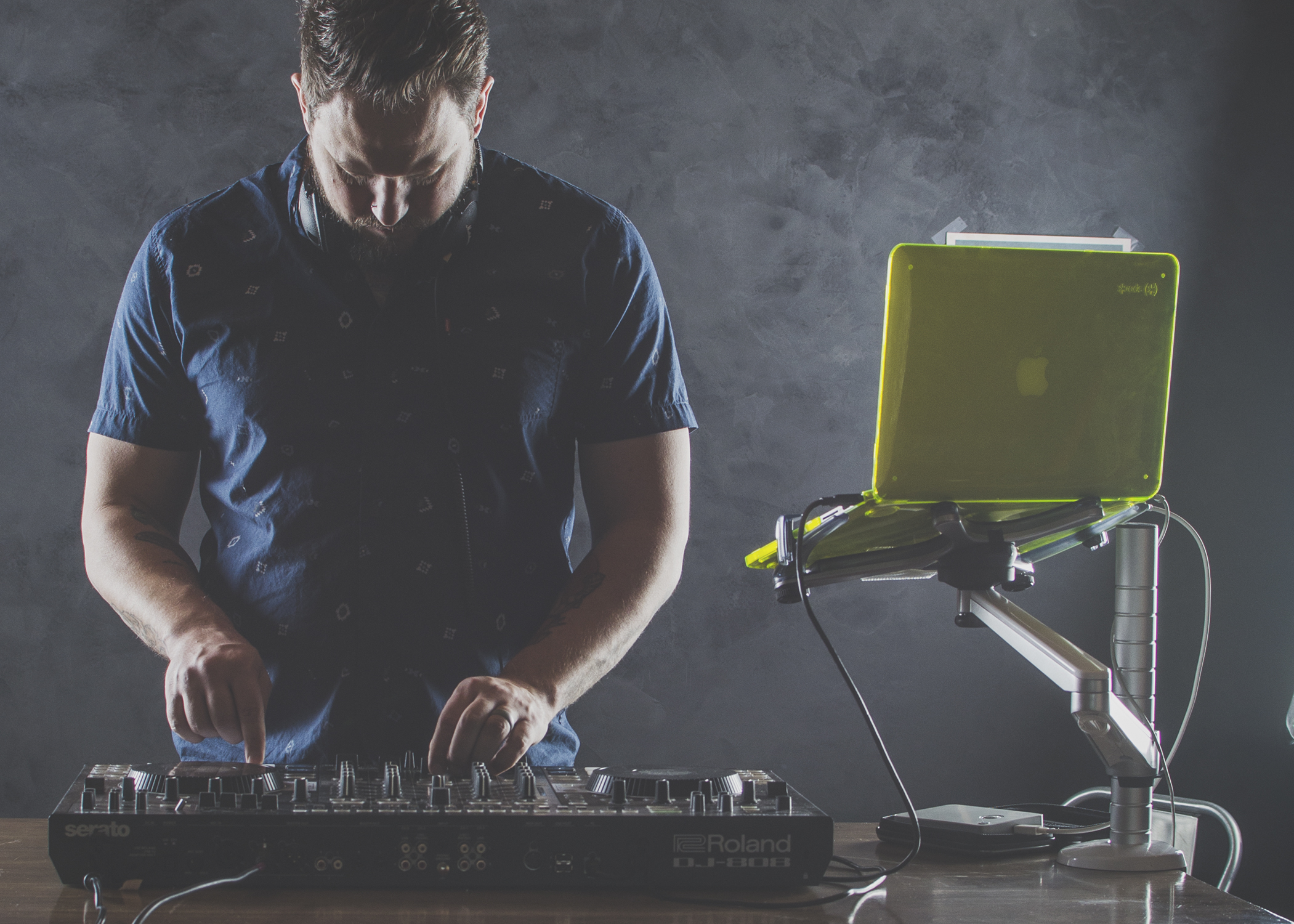 DJ Bear Cole focused over a Roland DJ controller beside his laptop